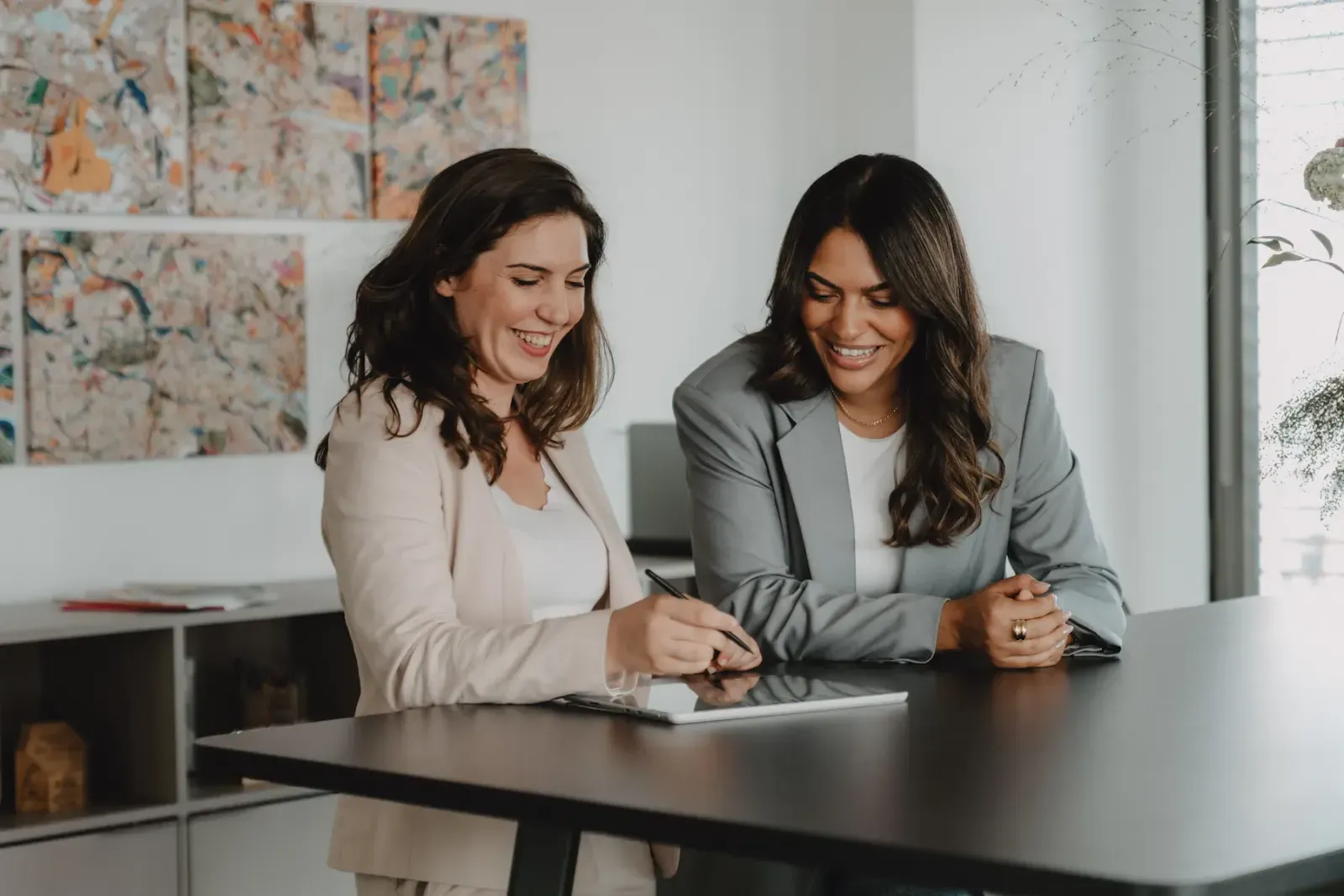 White Bird team: two women laughing while working on a tablet in the office