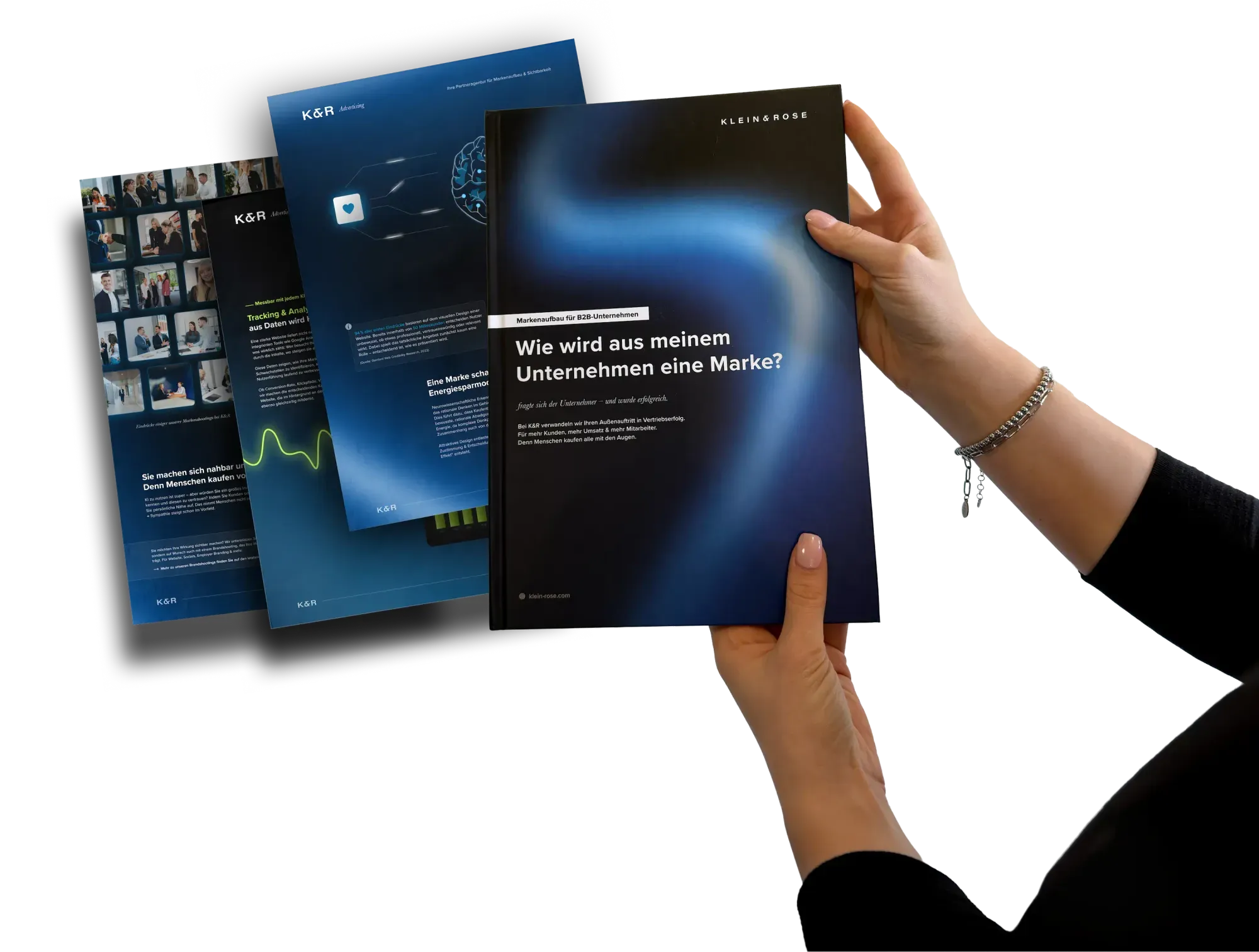 Haende halten K&R Markenhandbuch, Tablets mit Website-Designs im Hintergrund