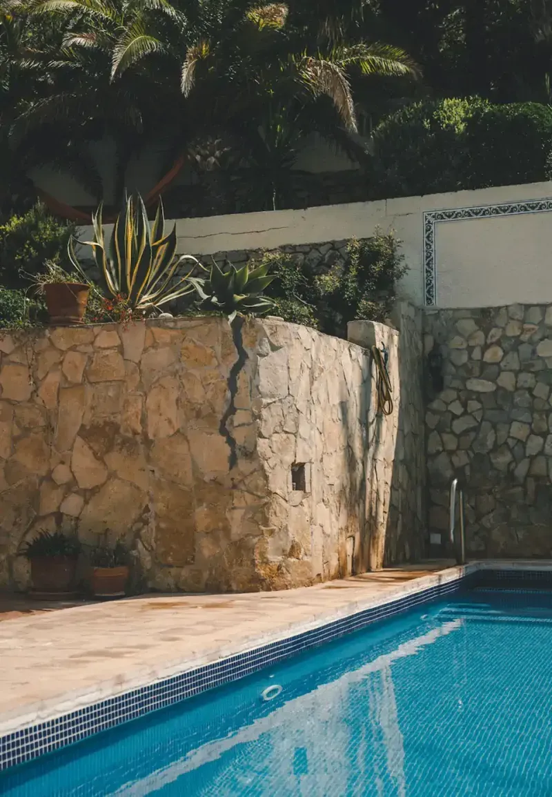 Pool mit blauem Mosaik neben Natursteinmauer, Palmen und Agaven – K&R Architekturfotografie Mittelmeer