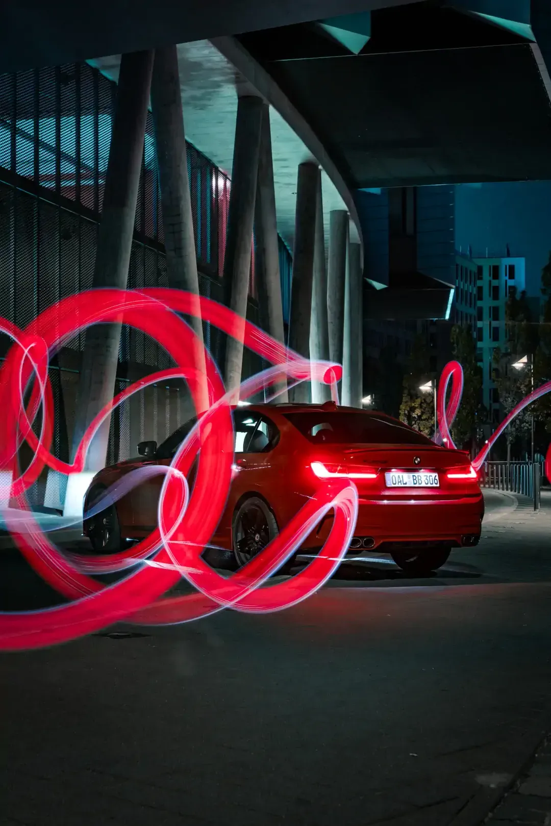 Roter BMW Alpina bei Nacht unter Betonstützen mit roten Lichtmalerei-Kreisen – Euler Alpina Days