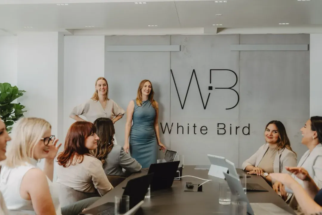 White Bird meeting room: women in front of a wall with the logo