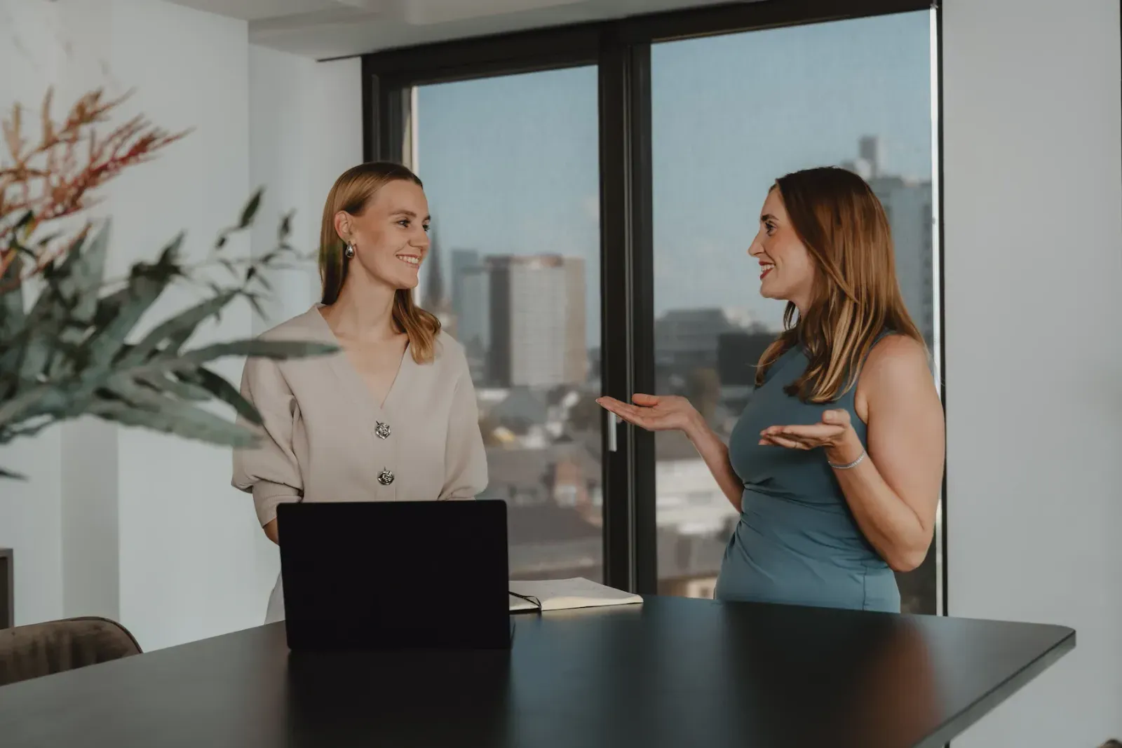 White Bird team: two women chatting cheerfully in the modern office