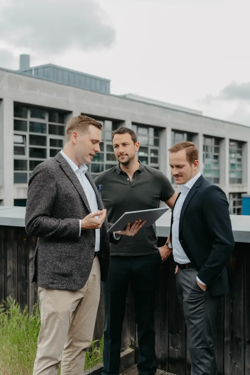 VAP team: three men with a tablet in front of a modern building in Frankfurt