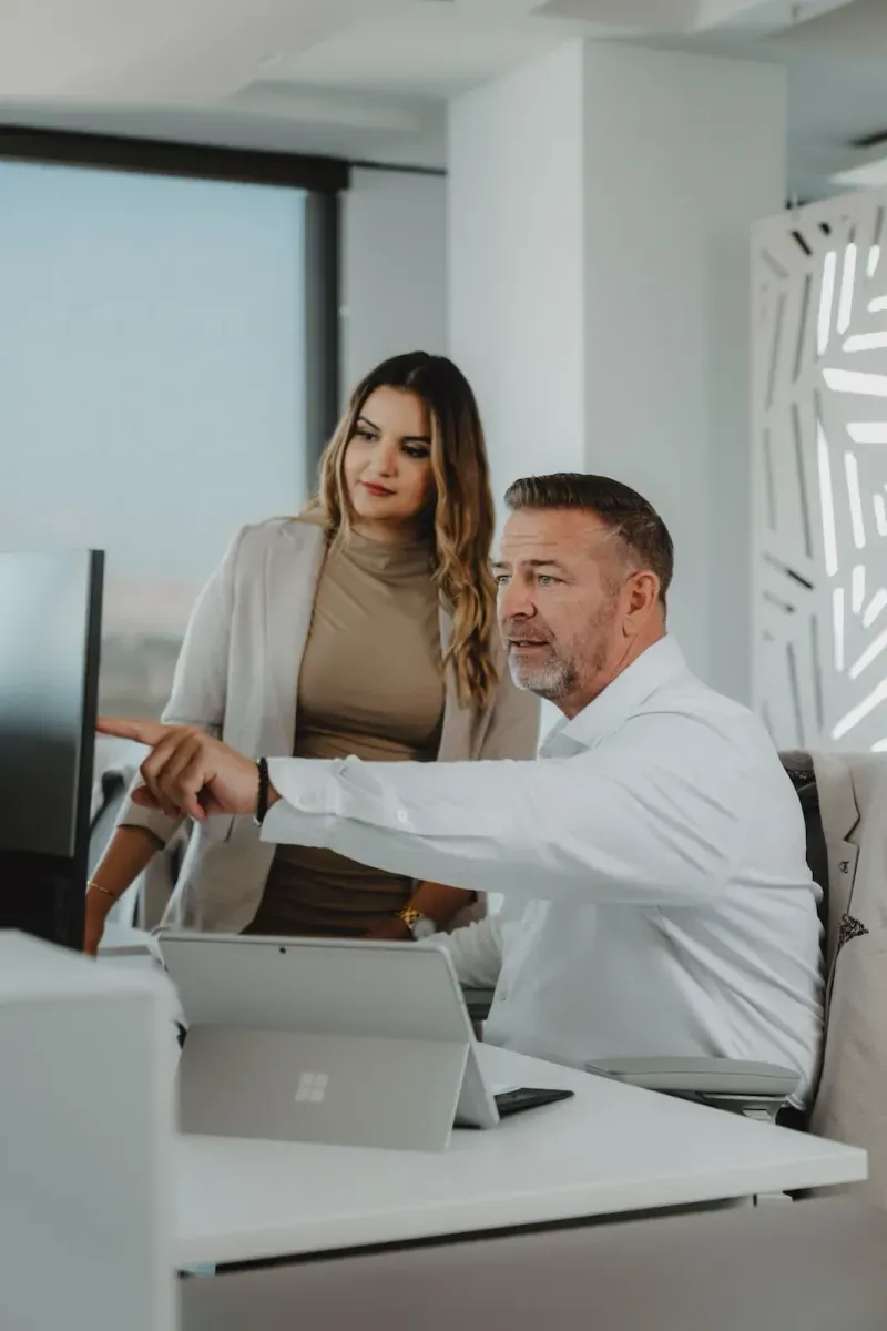 White Bird team: man pointing at a monitor while a colleague watches in the office