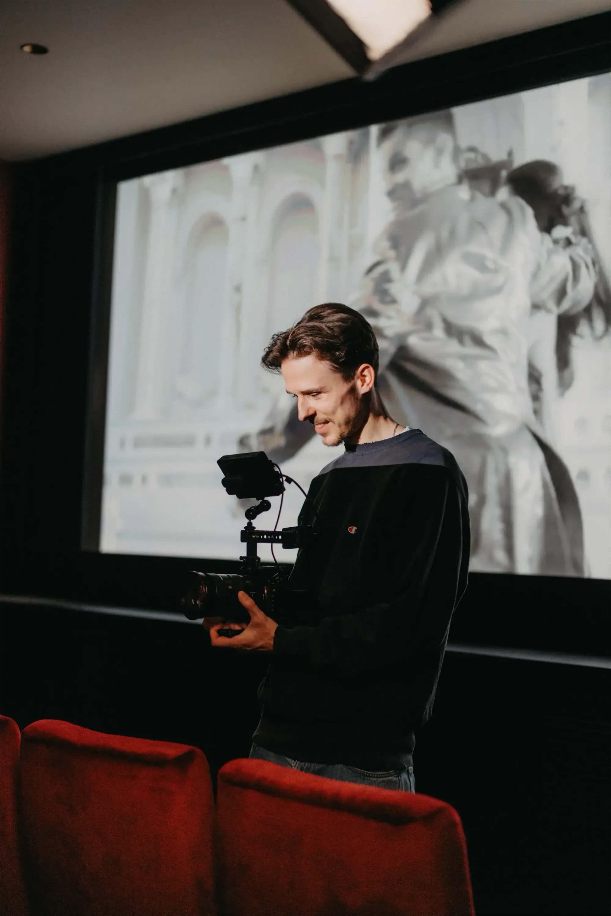K&R behind the scenes: cameraman with a video camera in front of a cinema screen